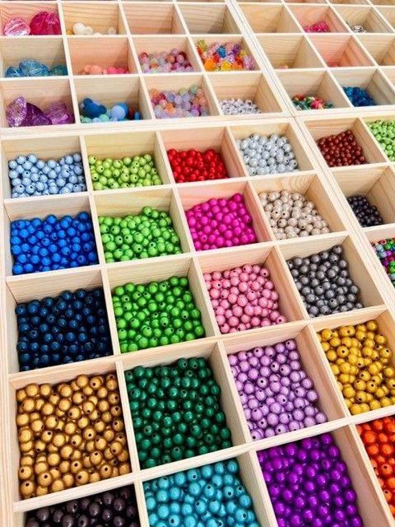 viele bunte Perlen in Holzfächern sortiert 